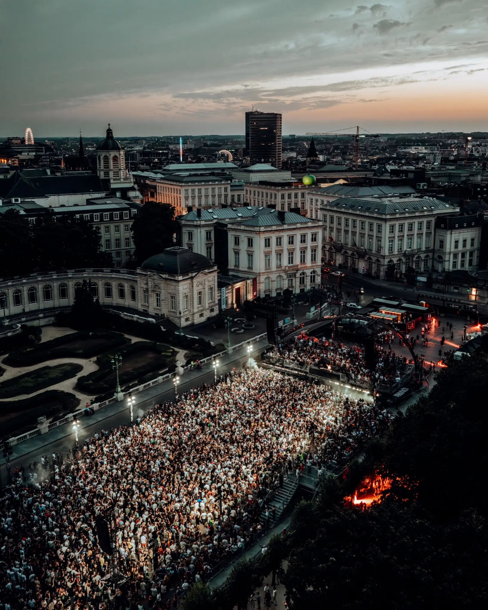 Aerial view at dusk of a crowd filling a square beside a palace in central Brussels
