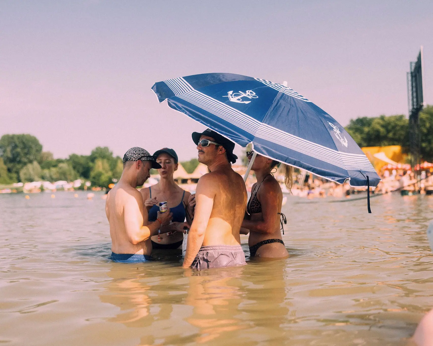Visitors standing in the lake under a beach parasol at Lago Lago