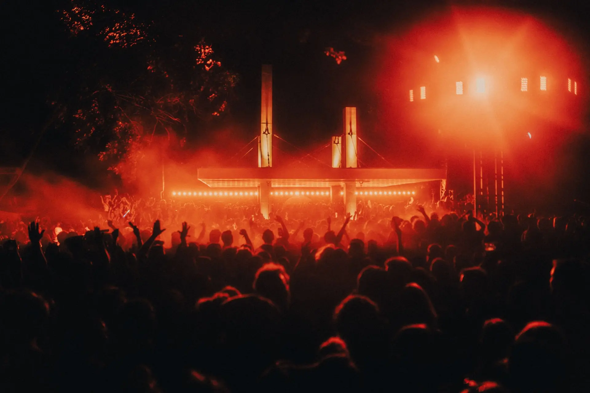 A crowd at Lago Lago’s night stage, lit red through the haze